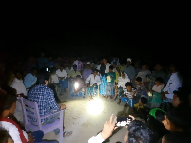 Political Mitra volunteer speaking with a small group of people at an evening gathering